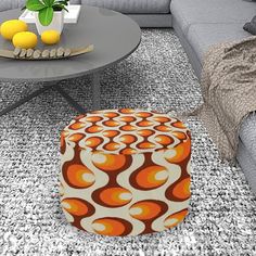 an orange and white ottoman sitting on top of a rug next to a gray couch