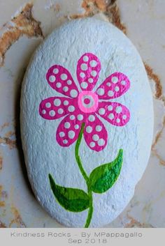 a painted rock with a pink flower on it