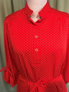 "This is an adorable vintage, blouse from the 1960s or 70s. No labels or tags. The bust measures 40\" with measurements below. Made of polyester fabric, it is a pretty red polka dot pattern. It has a small mandarin style collar, 1/2 button placket, 3/4 length sleeves with ties. Sleeves can be tied up for a gathered look or left down for a longer look. It is tunic length with a shirt tail hemline. It has a cord sash belt & fabric belt loops. The blouse is in very good condition! No holes, wea Vintage Fashion Long Sleeve Summer Blouse, Vintage Fashion Summer Long Sleeve Blouse, Summer Vintage Fashion Long Sleeve Blouse, Long Sleeve Blouse For Vintage Summer Fashion, Vintage Polka Dot Blouse For Spring, Retro Polka Dot Tops For Spring, Spring Polka Dot Retro Tops, 1970s Long Sleeve Summer Tops, Vintage Polka Dot Tops For Spring