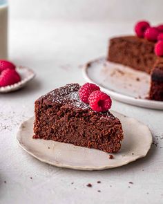 two plates with slices of chocolate cake and raspberries