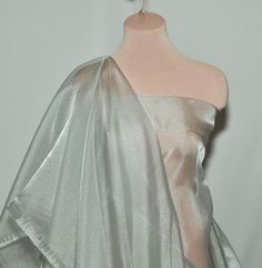 a white dress on a mannequin with a silver shawl draped over it