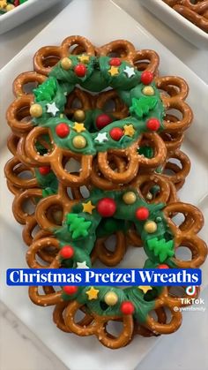 pretzels decorated with christmas decorations on a white platter next to other holiday treats