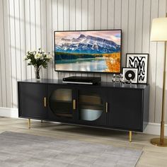 a flat screen tv sitting on top of a black entertainment center next to a lamp