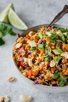 a bowl filled with rice and vegetables next to some lime wedges on the side