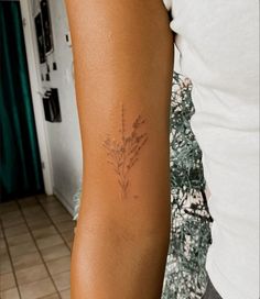 a woman's arm with a small flower tattoo on the left side of her right arm