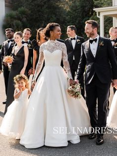 a bride and groom walking with their flower girls in front of the wedding party wearing tuxedos