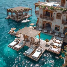 an aerial view of a house on stilts in the ocean with sun beds and lounge chairs