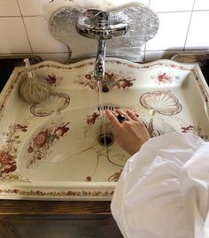 a person is washing their hands in a sink with flowers on the bottom and sides