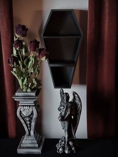 two vases with roses and an animal statue next to a wall mounted book shelf