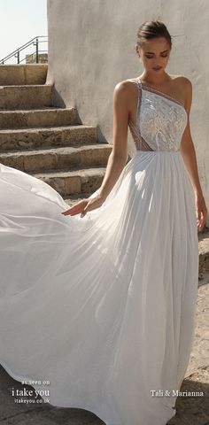 a woman in a white dress walking down some steps with her hand on her hip