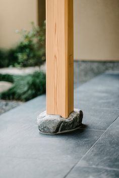 a wooden post sitting on top of a stone covered ground next to a planter