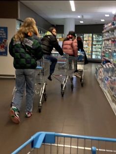 two women pushing a shopping cart through a grocery store aisle with people in the background