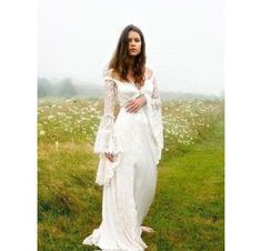 a woman standing in a field wearing a white dress and holding her hands on her hips