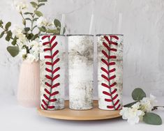 three baseball candles with red laces on them sitting on a plate next to flowers