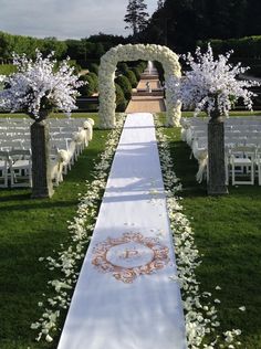 the aisle is decorated with white flowers and greenery