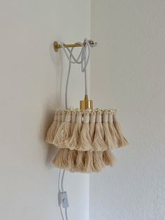 a small purse hanging from a hook on a white wall with a cord attached to it