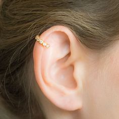 a close up of a person's ear with a gold ring on top of it