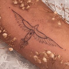 a tattoo on the leg of a woman with flowers in front of her and an image of a bird flying