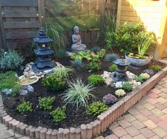 a small garden with buddha statues and plants