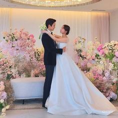 a bride and groom standing next to each other in front of flowers