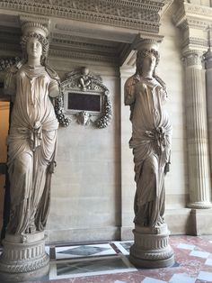 two statues are standing next to each other in a room with marble walls and flooring