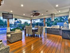 an outdoor kitchen and dining area with wood flooring, large windows, and ceiling fan