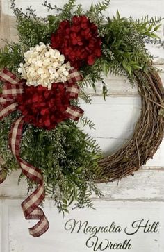 a wreath with red and white flowers is hanging on a wooden wall next to the words magnolia hill wreath