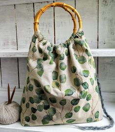 a bamboo handle bag sitting on top of a shelf next to a ball of yarn