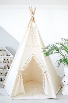 a white teepee tent sitting next to a potted plant