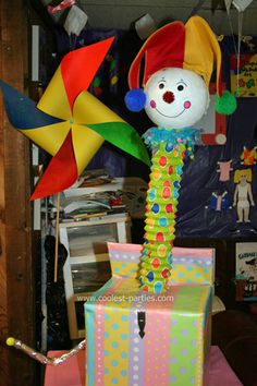 the clown is holding a colorful kite in his hand and standing on top of a gift box