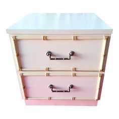 a pink and white chest of drawers with bamboo handles on each drawer, against a white background