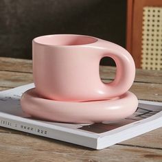 a pink coffee cup sitting on top of a book