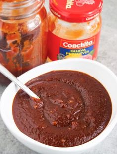 a white bowl filled with sauce next to a jar of condiments