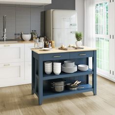 a blue kitchen island with plates and bowls on it in front of a white refrigerator