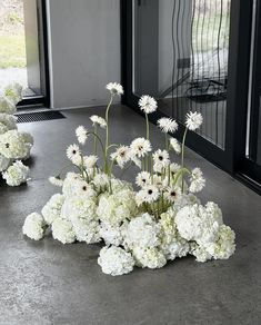 white flowers are arranged on the ground in front of an open door