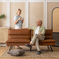 a man sitting on a couch next to a woman with a cup in her hand