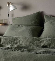 a bed with green linens and a white lamp