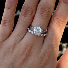 a woman's hand with a diamond ring on top of her finger and the other hand holding an engagement ring