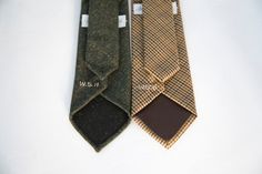 two ties that are sitting next to each other on a white surface, one is brown and the other is green