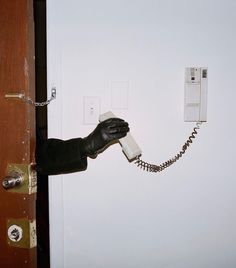 a person in black gloves is holding a phone up to a wall with a telephone on it