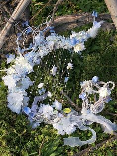 an arrangement of blue and white flowers on the ground next to a wooden structure with chains hanging from it's sides