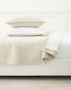 a bed with white sheets and pillows on it