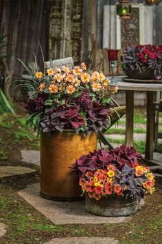 two buckets filled with colorful flowers sitting on top of a table next to each other