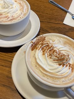 two white plates topped with hot chocolate and whipped cream