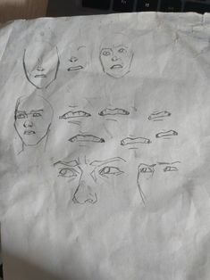 a piece of paper with drawings of people's faces on it and a computer keyboard in the background