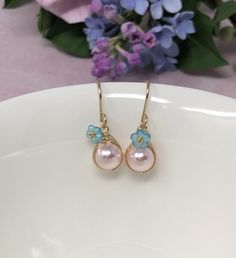 These one of a kind flowering beauties feature soft, blush pink Swarovski Crystal pearls that are meticulously wrapped in 14kt yellow gold filled wire. The braided detailing looks amazing with these pearls. Accented with gold-dusted, aqua Czech glass flowers and gracefully suspended from handcrafted French ear wires. These are perfect for Spring, Summer and for bridesmaids gifts! - All components are 14kt yellow gold filled. - Swarovski Crystal pearls, Czech Glass flower beads. - Pearl dangles a Glass Flower Earrings, Earrings Gold Pearl, Pink Pearl Earrings, Pearl Earrings Gold, Pearl Drop Earrings Gold, Malachite Earrings, Easter Earrings, Lapis Lazuli Jewelry, Spring Earrings