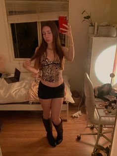 a young woman taking a selfie in her bedroom while wearing short shorts and boots