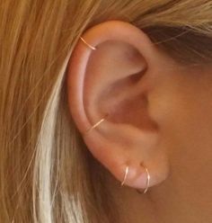 a woman's ear is shown with two small gold hoops