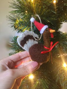 a hand holding a christmas ornament in front of a tree