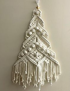 a white christmas tree hanging on the wall with beads and tassels attached to it